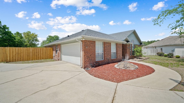 view of home's exterior with roof with shingles, fence, brick siding, an attached garage, and concrete driveway