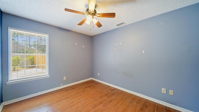 empty room featuring baseboards, a textured ceiling, visible vents, ceiling fan, and wood finished floors