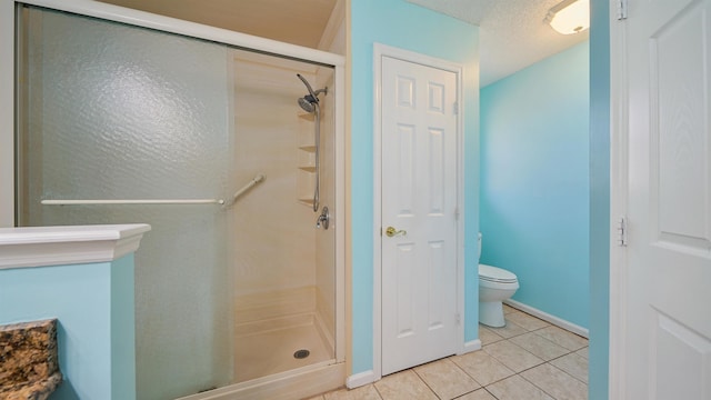 bathroom with toilet, tile patterned floors, a shower stall, and baseboards