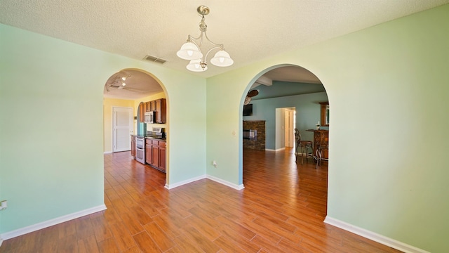 unfurnished dining area featuring visible vents, baseboards, an inviting chandelier, and wood finished floors