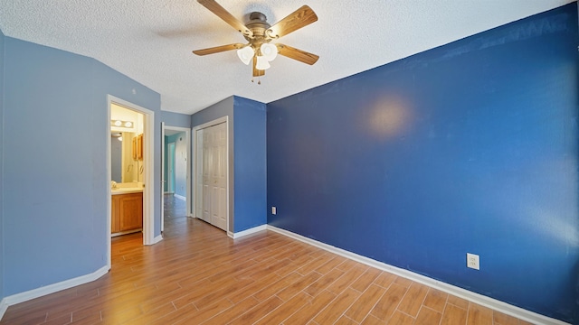 unfurnished bedroom featuring a closet, baseboards, ceiling fan, a textured ceiling, and wood finished floors
