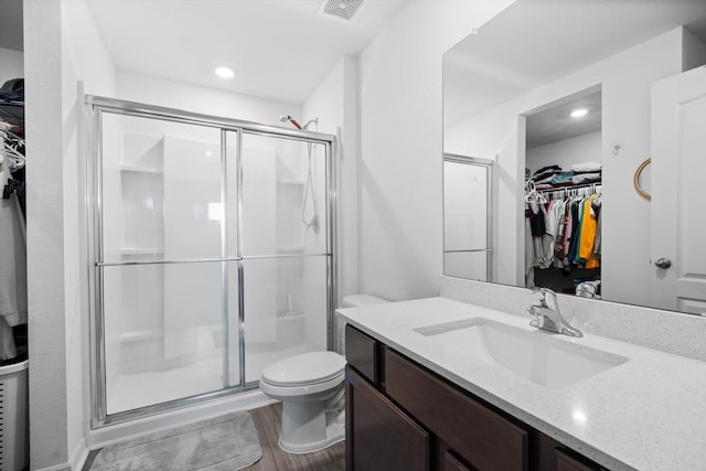 bathroom featuring a shower with door, vanity, hardwood / wood-style floors, and toilet