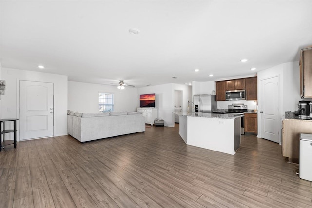 kitchen featuring sink, ceiling fan, stainless steel appliances, a center island with sink, and dark hardwood / wood-style flooring