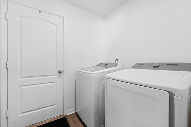 clothes washing area with separate washer and dryer and dark wood-type flooring