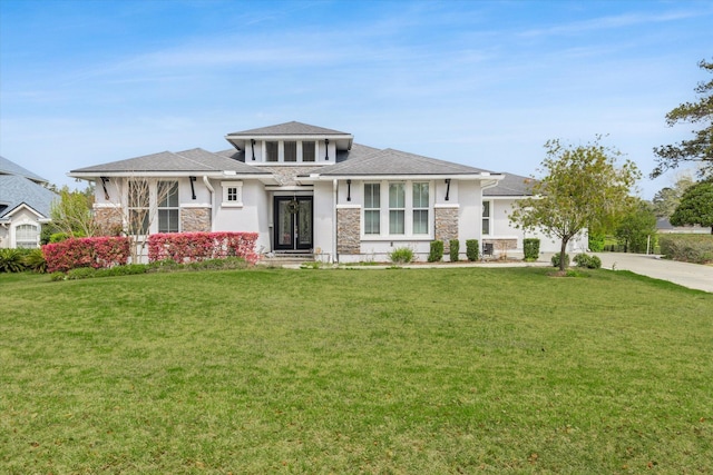 prairie-style home with stucco siding, a front lawn, stone siding, concrete driveway, and an attached garage