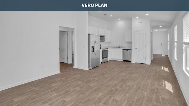 kitchen featuring appliances with stainless steel finishes, vaulted ceiling, light hardwood / wood-style floors, and white cabinetry