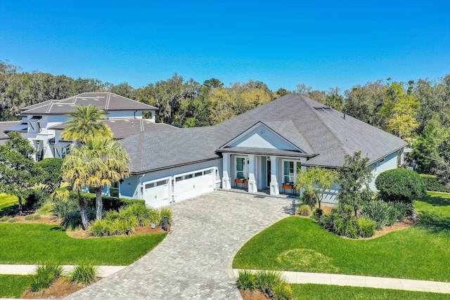 view of front of home with a front yard, decorative driveway, and a garage