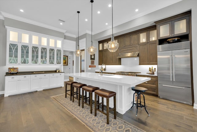 kitchen with dark wood finished floors, crown molding, appliances with stainless steel finishes, and a sink