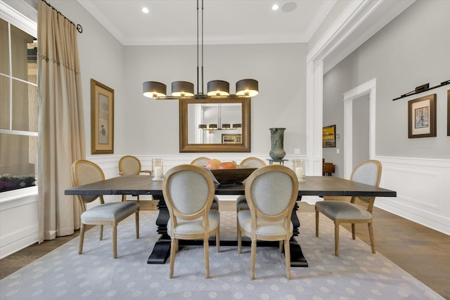 dining room featuring a wainscoted wall, ornamental molding, a decorative wall, and wood finished floors