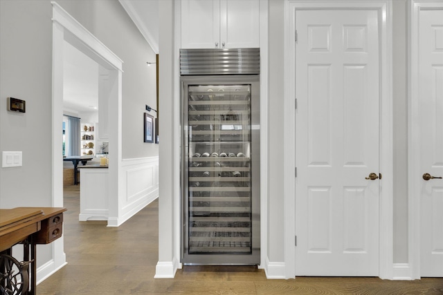 details featuring wine cooler, wainscoting, and wood finished floors