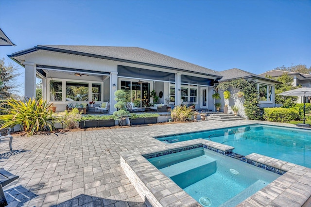 rear view of property featuring a ceiling fan, a patio area, a pool with connected hot tub, and roof with shingles