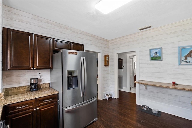 kitchen featuring dark brown cabinets, light stone counters, stainless steel refrigerator with ice dispenser, and dark wood-type flooring