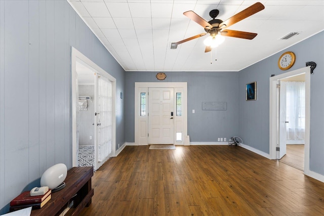 foyer entrance with dark hardwood / wood-style flooring, wooden walls, ceiling fan, and a healthy amount of sunlight