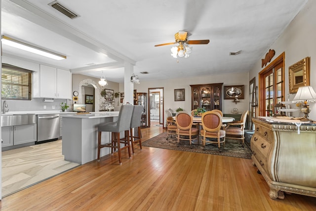 kitchen featuring stainless steel dishwasher, ceiling fan, light hardwood / wood-style flooring, white cabinets, and a center island