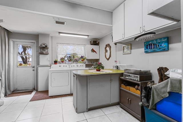 laundry area featuring separate washer and dryer, light tile patterned floors, and cabinets