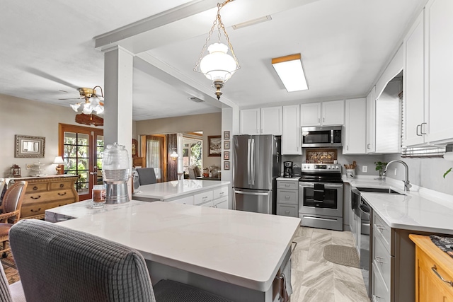 kitchen with white cabinets, ceiling fan, light stone countertops, and appliances with stainless steel finishes