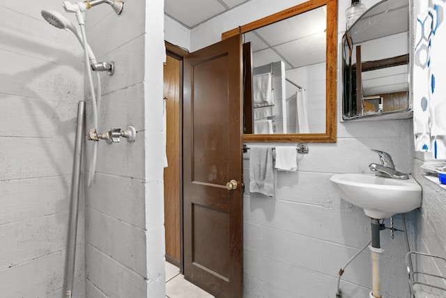 bathroom with a shower with shower curtain, a drop ceiling, and sink