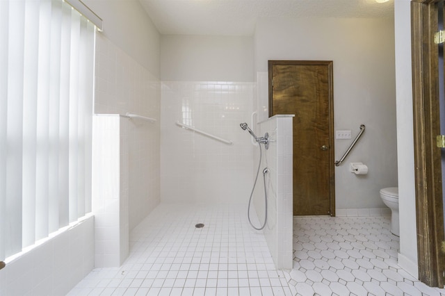 bathroom featuring tile patterned floors, toilet, a textured ceiling, and tiled shower