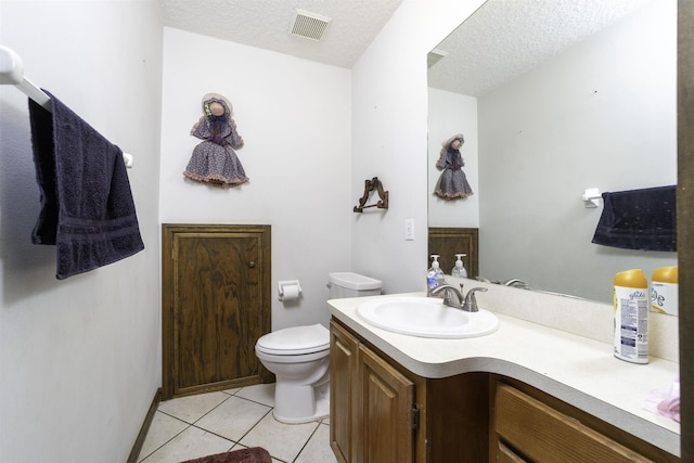 bathroom with tile patterned flooring, vanity, toilet, and a textured ceiling