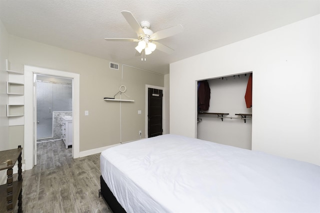 bedroom with hardwood / wood-style floors, ensuite bathroom, ceiling fan, a textured ceiling, and a closet