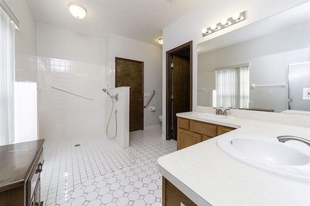 bathroom featuring a shower, vanity, a textured ceiling, and toilet