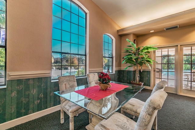 carpeted dining space with lofted ceiling and wooden walls