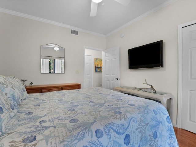 bedroom featuring a ceiling fan, visible vents, crown molding, and wood finished floors