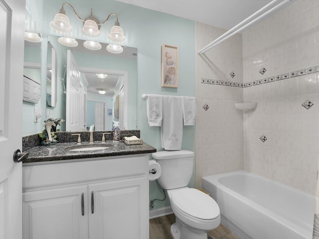 full bathroom featuring vanity, hardwood / wood-style floors, tiled shower / bath combo, and toilet