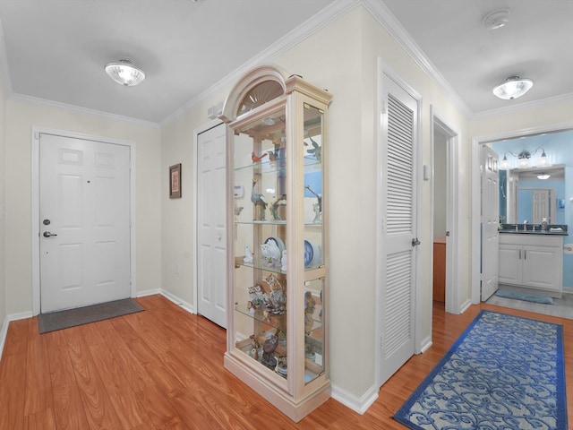 foyer with ornamental molding, baseboards, and light wood finished floors