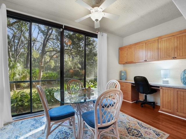 interior space featuring ceiling fan, a textured ceiling, dark wood-type flooring, and built in desk