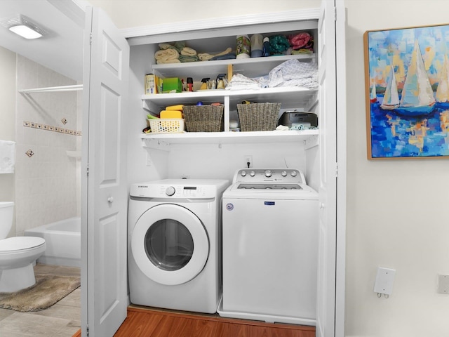 clothes washing area with independent washer and dryer and light hardwood / wood-style floors