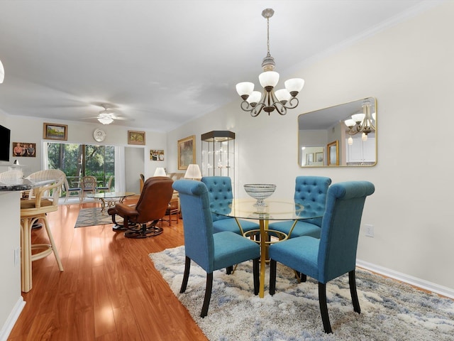 dining room with ceiling fan with notable chandelier, ornamental molding, wood finished floors, and baseboards