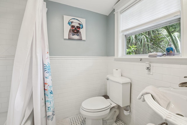 127 M L King Ave, Saint Augustine, FL 32084 - bathroom with tile walls, toilet, curtained shower, a wainscoted wall, and tile patterned floors