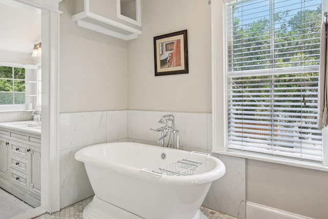 127 M L King Ave, Saint Augustine, FL 32084 - bathroom featuring healthy amount of natural light, a soaking tub, vanity, a wainscoted wall, and tile walls