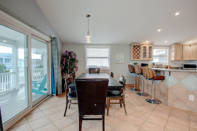 dining space featuring light tile patterned flooring, a healthy amount of sunlight, and vaulted ceiling