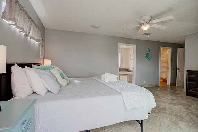 bedroom featuring ensuite bathroom, ceiling fan, light tile patterned floors, and a textured ceiling