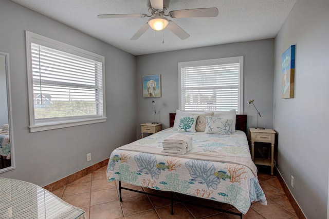 bedroom featuring ceiling fan, light tile patterned floors, and a textured ceiling