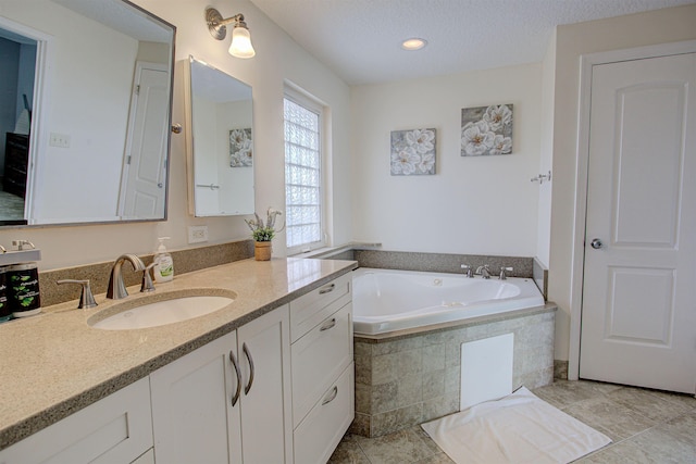 bathroom with a textured ceiling, vanity, tile patterned floors, and tiled tub