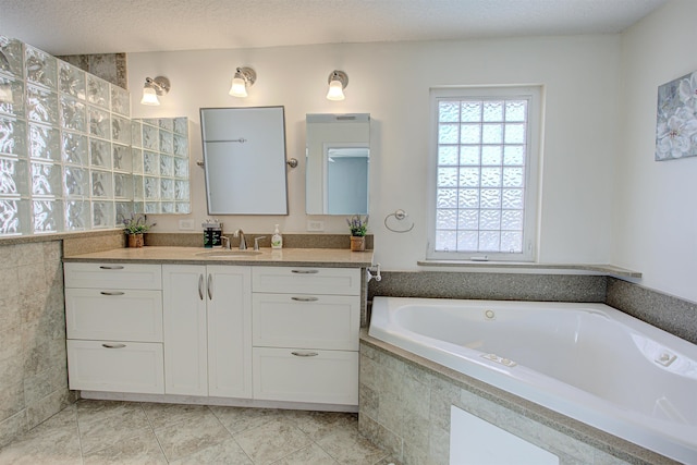 bathroom with vanity, a textured ceiling, a relaxing tiled tub, and tile patterned floors