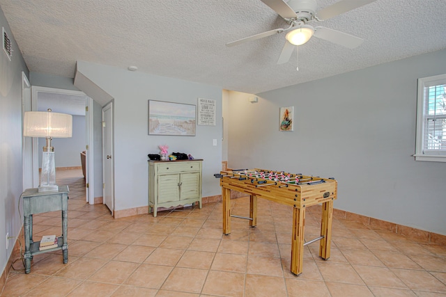 recreation room with ceiling fan, light tile patterned floors, and a textured ceiling