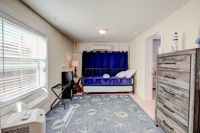 bedroom featuring a wall mounted air conditioner, concrete floors, and a textured ceiling