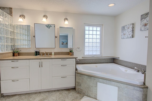 bathroom with vanity, a textured ceiling, tiled bath, and tile patterned floors