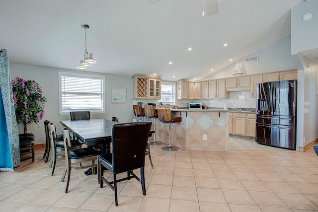 tiled dining area featuring sink, a healthy amount of sunlight, and vaulted ceiling