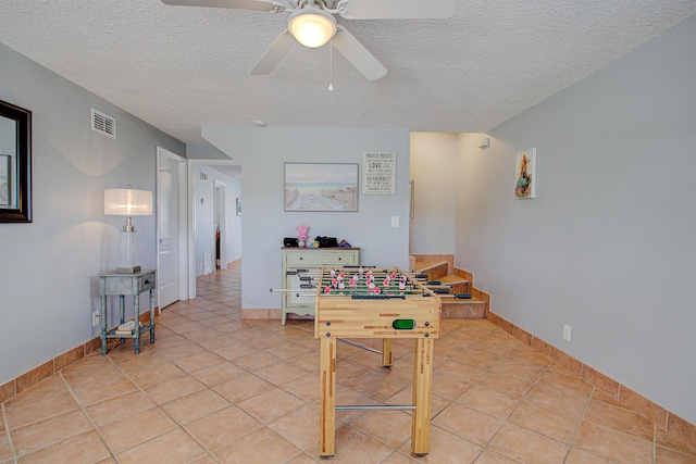 recreation room with ceiling fan, light tile patterned flooring, and a textured ceiling