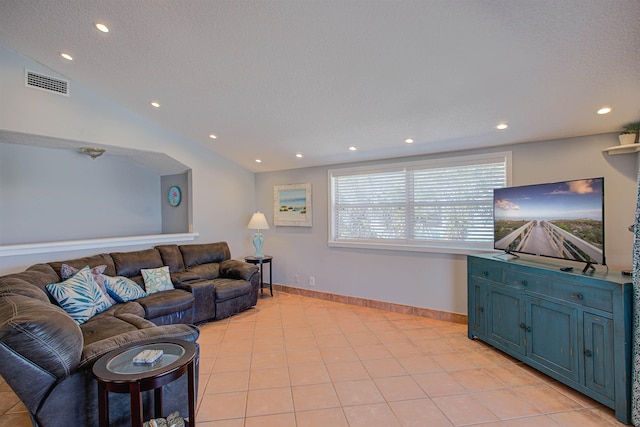 living room with a textured ceiling, lofted ceiling, and light tile patterned flooring