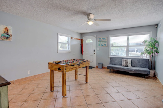 rec room featuring ceiling fan, light tile patterned floors, and a textured ceiling