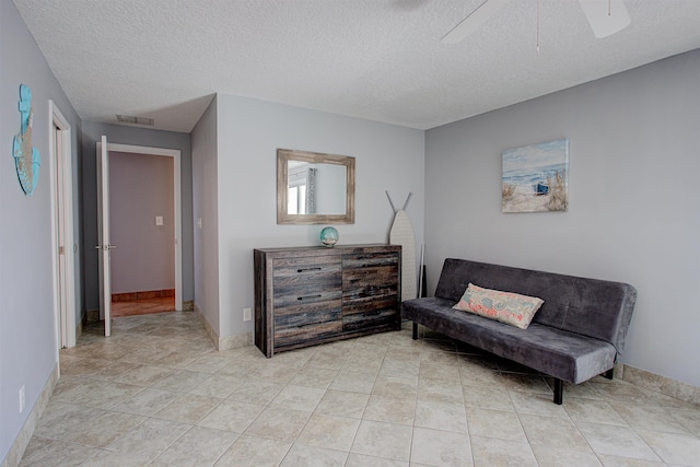 sitting room featuring ceiling fan, light tile patterned flooring, and a textured ceiling