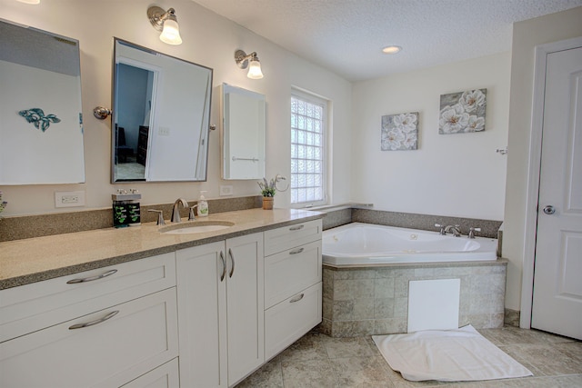 bathroom with tile patterned flooring, vanity, a relaxing tiled tub, and a textured ceiling