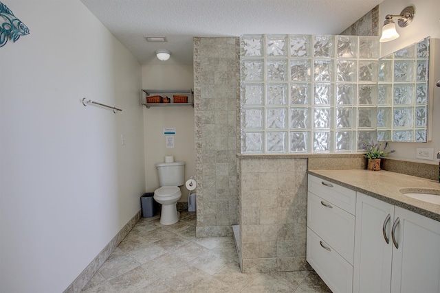 bathroom featuring tile patterned flooring, vanity, toilet, and a textured ceiling