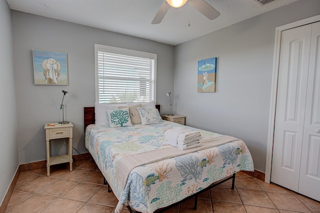 tiled bedroom with ceiling fan, a closet, and a textured ceiling